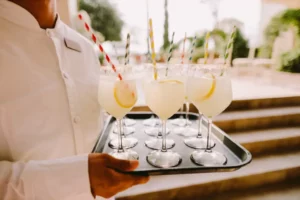 Un chelner ține în mâini o tava cu pahare pline cu limonadă