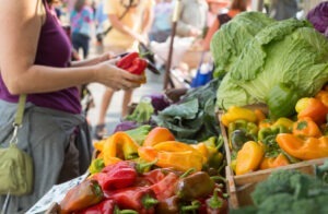O femeie analizează legume într-o piață