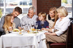 O familie ia masa împreună. Zâmbesc și sunt relaxați