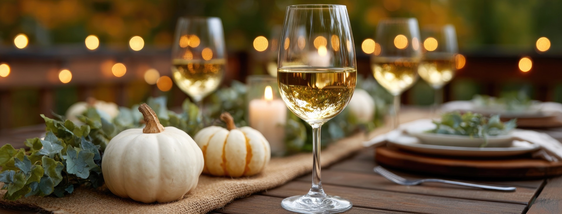 Masă decorată de toamnă, un pahar de vin, dovleci
